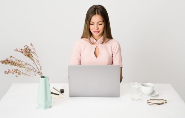 Умная девушка за ноутбуком на сером фоне