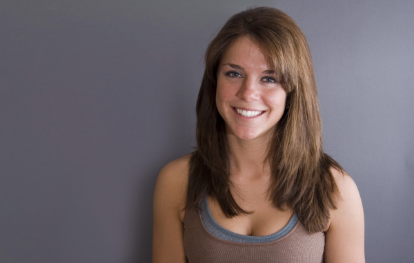 Улыбающаяся милая девушка у серой стены