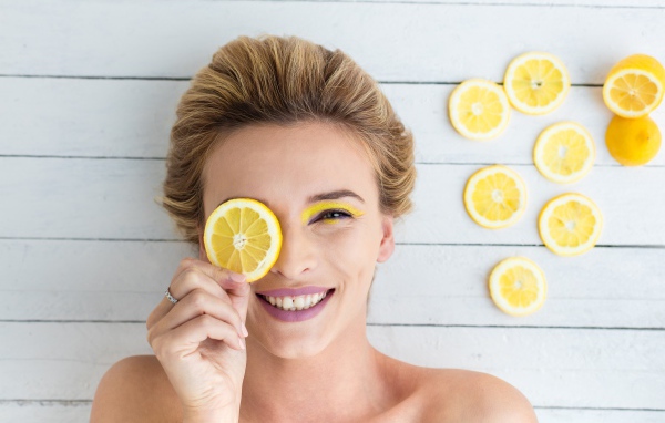 Улыбающаяся девушка приложила лимон к глазу