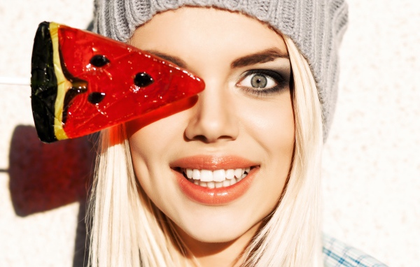 Улыбающаяся девушка с леденцом в руке крупным планом