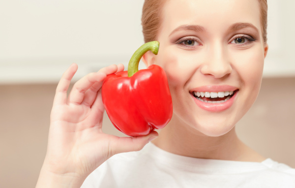 Улыбающаяся девушка с красным сладким перцем в руке