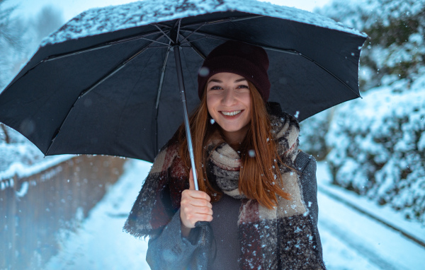 Улыбающаяся молодая девушка под зонтом зимой