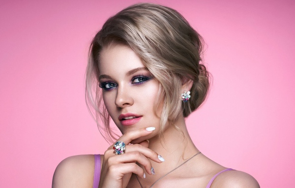 Стильная блондинка с прической на розовом фоне