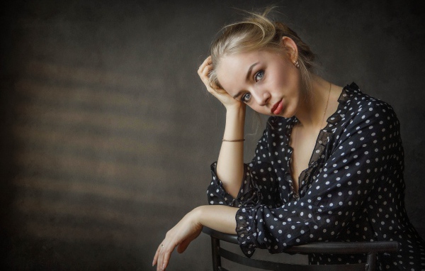 Нежная девушка блондинка сидит на стуле