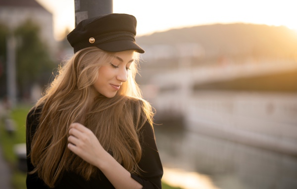 Нежная девушка в черной кепке в лучах солнца
