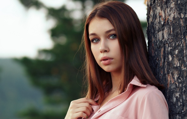 Нежная девушка стоит у дерева