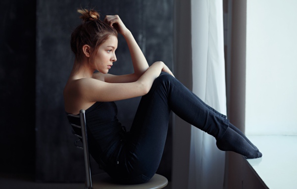 Девушка в черном наряде сидит на стуле