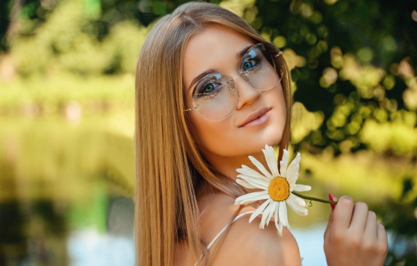 Девушка в очках с ромашкой в руке 