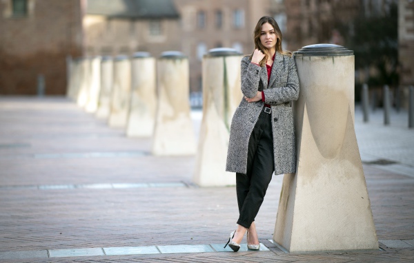 Девушка стоит в сером пальто 