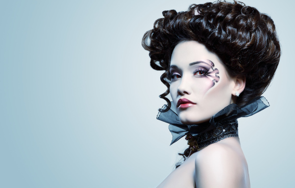 Девушка с необыной прической и макияжем на сером фоне