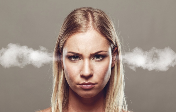 Дым из ушей у девушки блондинки на сером фоне
