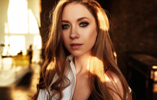 Лучи солнца нападают на волосы голубоглазой шатенки 