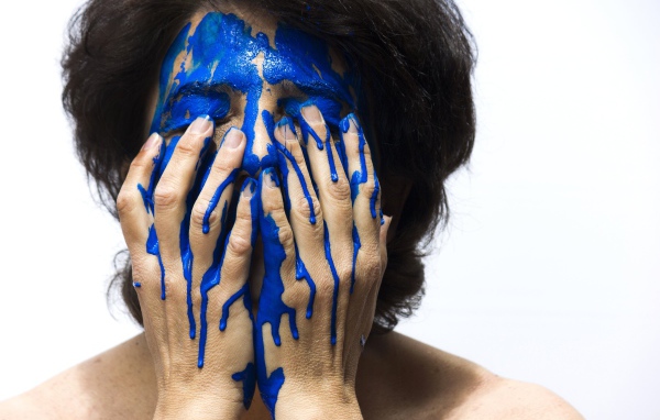 Лицо и руки женщины в синей краске