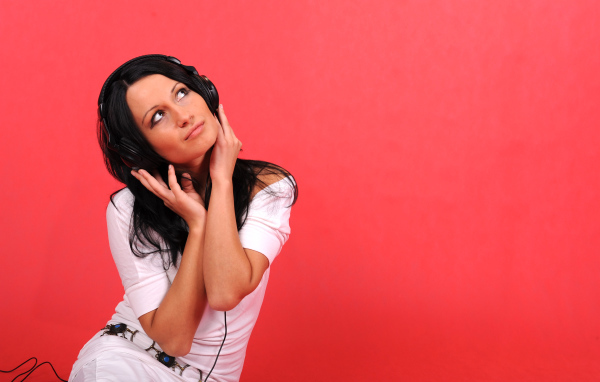 Молодая девушка в наушниках на красном фоне