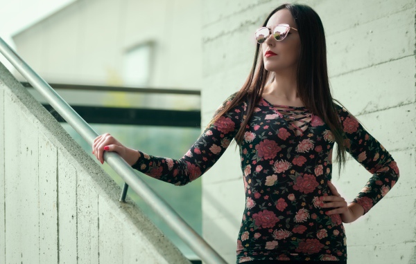 Молодая девушка в солнечных очках стоит на ступеньках