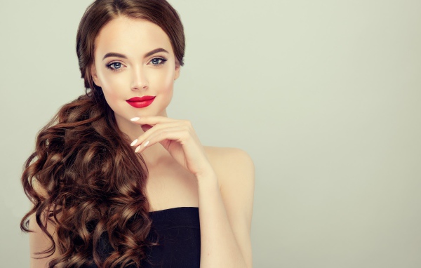Молодая девушка с красивыми волосами на сером фоне