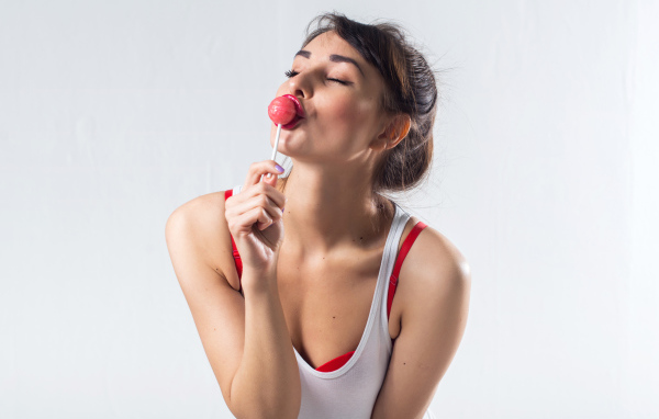 Молодая девушка с конфетой на палочке