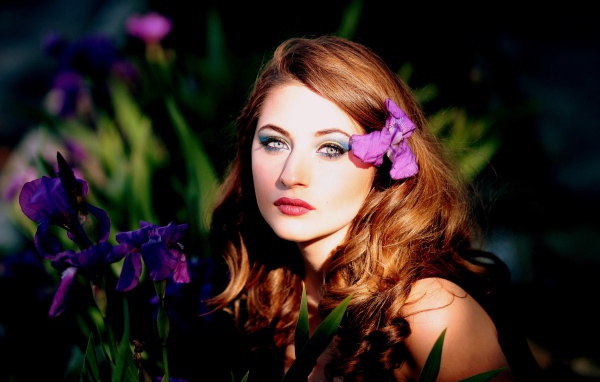 Молодая девушка с фиолетовым цветком ириса в волосах