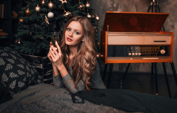 Красивая девушка с фужером шампанского у новогодней елки