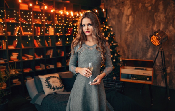 Красивая девушка с бокалом шампанского в комнате украшенной гирляндой