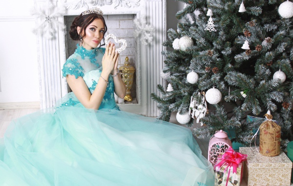 Young girl in a beautiful blue dress near the New Year tree