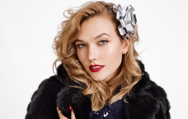 Модель Карли Клосс в черной шубе на белом фоне