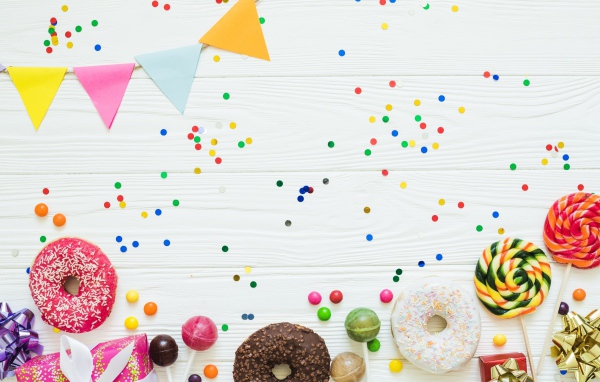Пончики с глазурью и конфеты на праздничном фоне