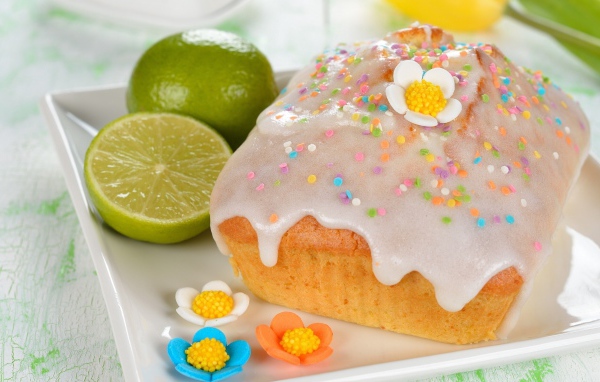 Красивый пасхальный кулич на белой тарелке с лаймом и сахарными цветами