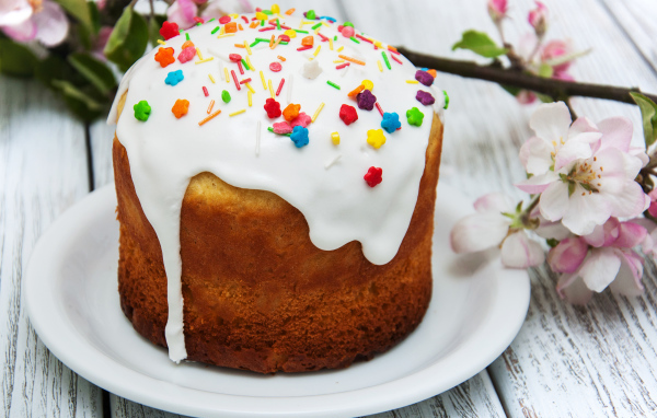 Красивый кулич с белой глазурью на столе с веткой яблони на Великий праздник Пасха