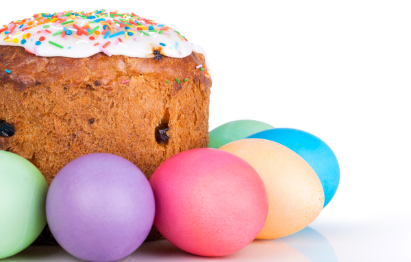 Пасхальный кулич с изюмом на белом фоне с крашеными яйцами 