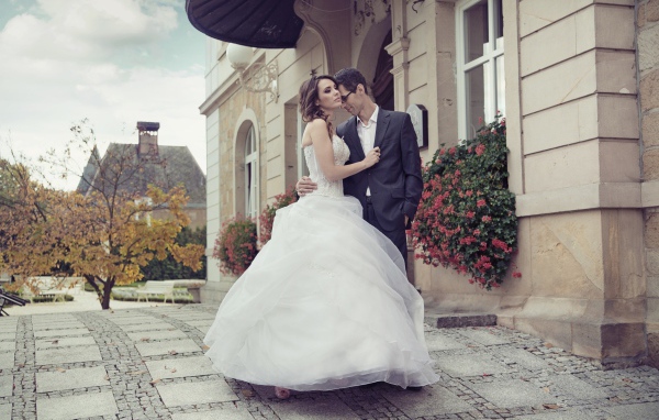 Жених и невеста стоят у здания 