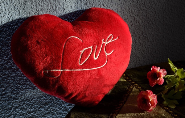 Большое плюшевое красное сердце у стены 