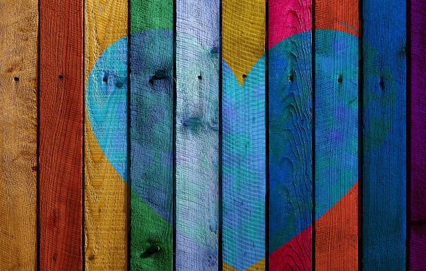 Голубое сердце нарисовано на разноцветном заборе