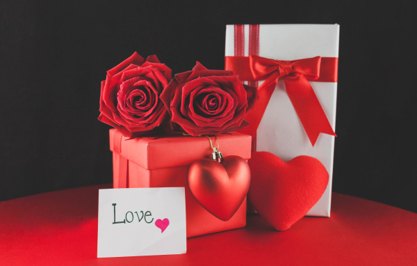 Коробки с подарками на столе с красными розами и сердцем