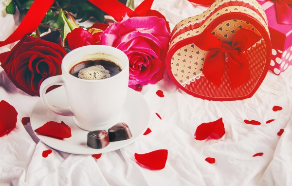 Коробка в форме сердца на белой ткани с чашкой кофе и розами