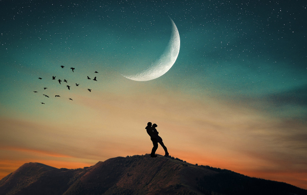 Влюбленная пара стоит на горе на фоне луны 