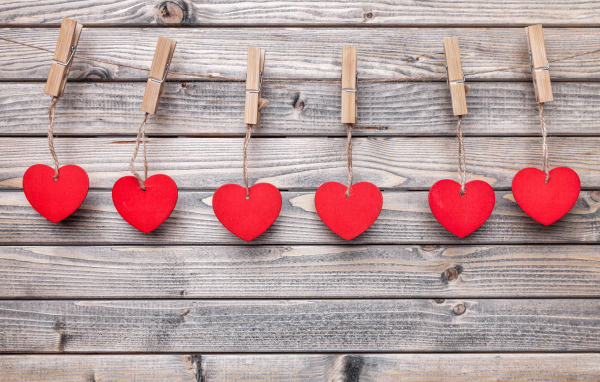 Красные сердечки на прищепках на деревянном столе 