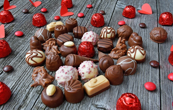 Сладкое сердце из шоколадных конфет на деревянном столе