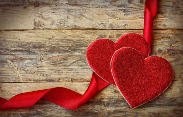 Два сердца с красной лентой на деревянном столе