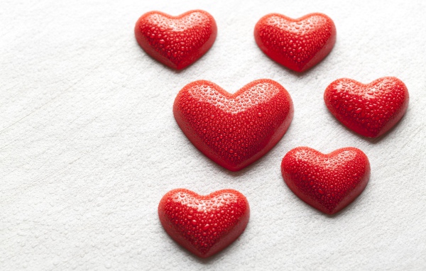 Мокрые красные сердечки на белой поверхности 