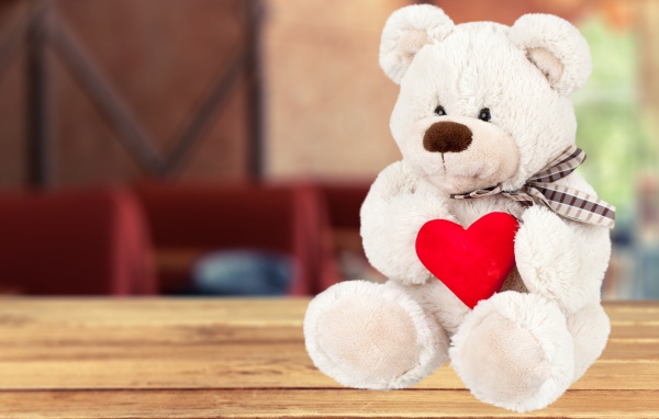 Белый плюшевый мишка с красным сердцем
