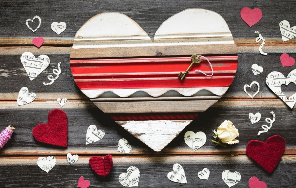 Деревянное сердце с бумажными сердечками на столе