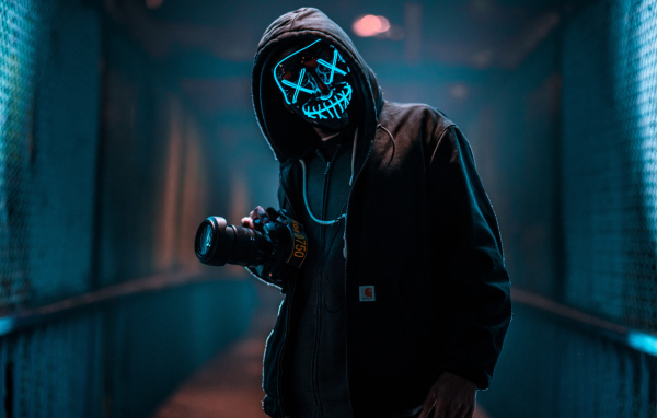 A guy in an anonymous neon mask with a camera