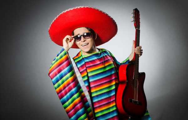 Мужчина в красном сомбреро с гитарой в руках на сером фоне