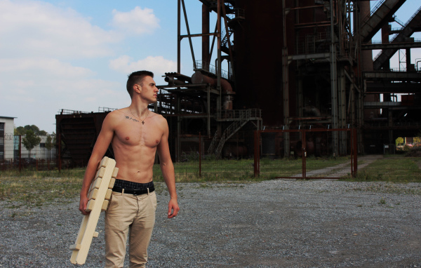 Красивый молодой парень стоит на фоне завода