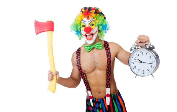 Man in a clown suit with an ax and a clock in his hand on a white background
