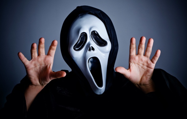 Мужчина в маске пугает на сером фоне