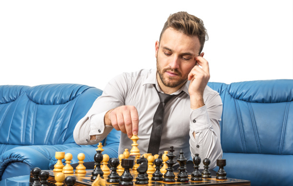 Мужчина играет в шахматы на синем диване
