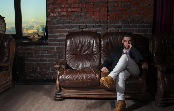 Стильный мужчина сидит в кожаном кресле 