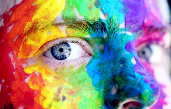 Лицо голубоглазого мужчины в разноцветных красках крупным планом